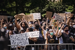 [ai] A diverse crowd of protesters holding signs at a rally, many wearing masks. Signs include messages like "Justice for George Floyd" and "Black Lives Matter," with people raising their fists in solidarity.