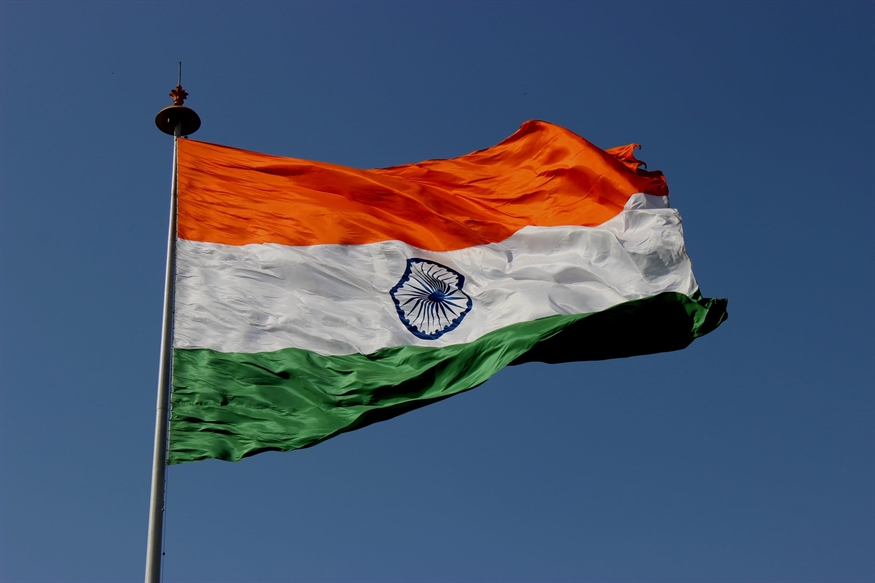 [ai] The Indian national flag waving in the wind, displaying its three horizontal bands of saffron, white, and green, with the Ashoka Chakra in navy blue in the center.